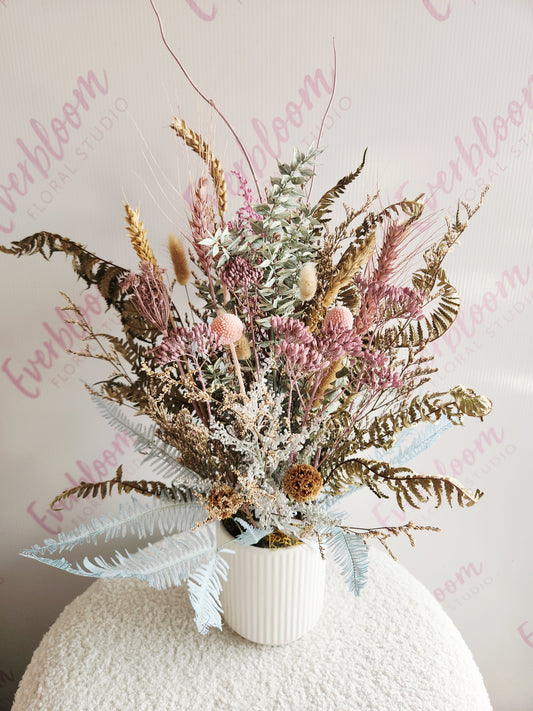 Dried floral arrangement in dusky pinks, natural brown tones with a soft hint of blue created in a white ceramic pot.
Everbloom Floral Studio, Your favourite Papamoa florist