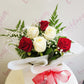Red and white rose bouquet wrapped in soft white paper in flower bag with red bow. Tauranga Florist - Everbloom floral studio