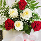 Red and white rose bouquet wrapped in soft white paper in flower bag with red bow. Tauranga Florist - Everbloom floral studio