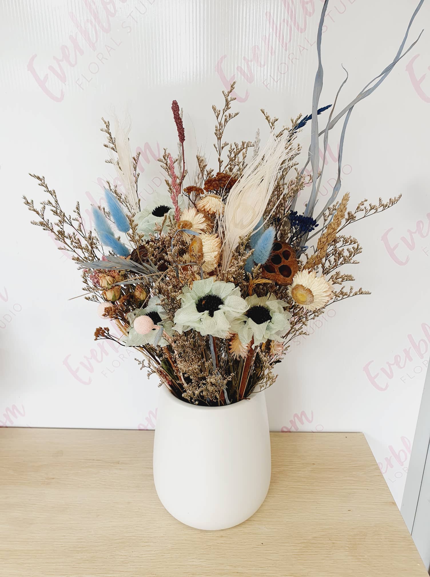 Our dried flower arrangements now come in white vases, Simply receive, display and enjoy, no fuss finding the right height vase for your flowers. Dried arrangements may slightly vary due to availability and colour but for the most part will stay similar to the pictures provided. A mix of strawflowers, caspea, spray roses, anenomes, lotus pods and wild flowers. Same day flower delivery from our sunny mount maunganui floral studio.